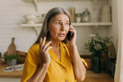 Elderly adorable Caucasian grandmother talking on phone with her