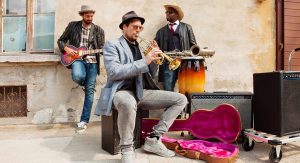 A blues band is jamming out on the side of the street looking real relaxed.