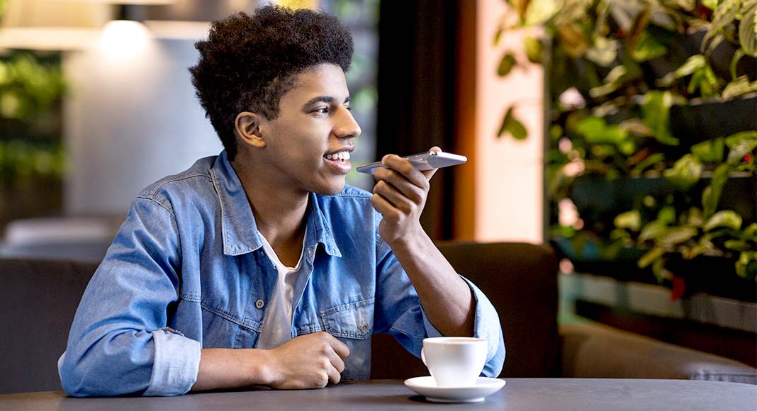 Young man sitting at café and speaking into phone