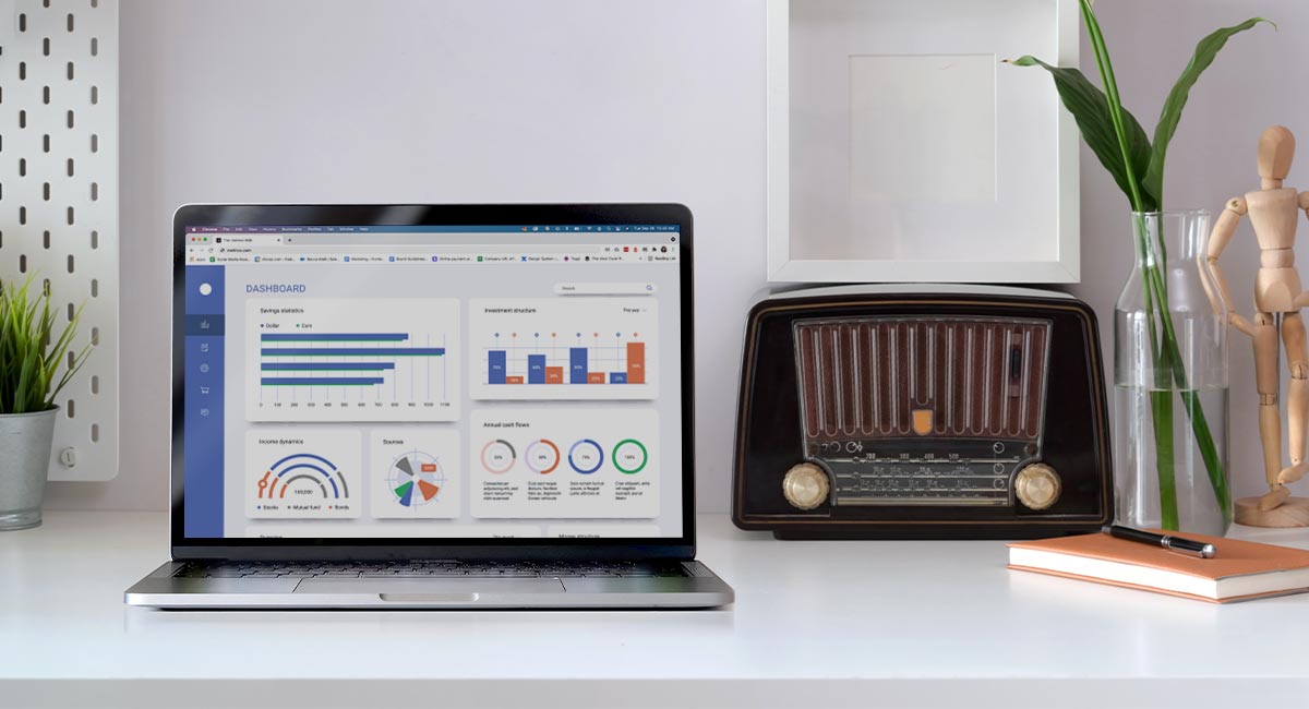 A laptop with analytics on the screen next to a radio