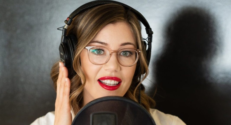 A list of dramatic monologues for women represented by a woman with brunette hair and glasses holding her hand against her headphones as she speaks into a microphone.