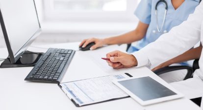 Doctors reviewing reports in front of a computer.