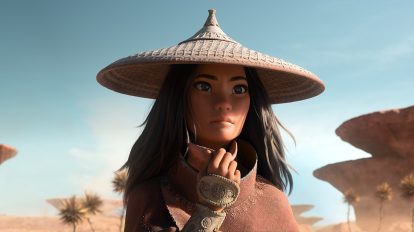 Raya wears a hat in the desert and is pulling her mask down.