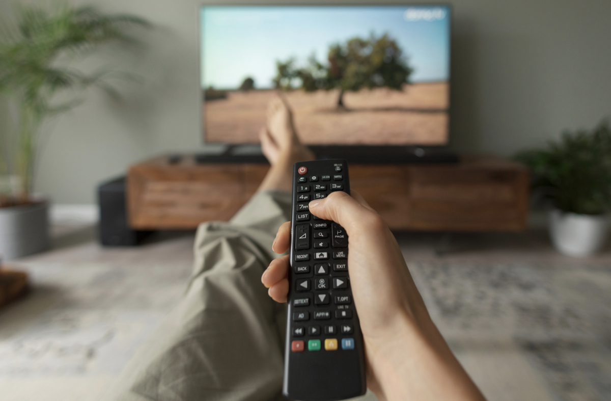 Person holding tv remote control with their feet up.