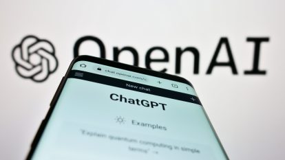A photo of a cellphone with ChatGPT's website open and OpenAI's logo in the background.
