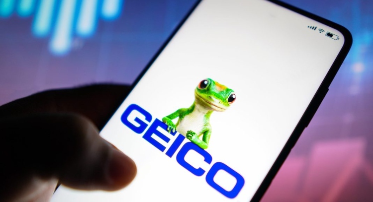 The Geico Gecko along with the word Geico on a smartphone screen.