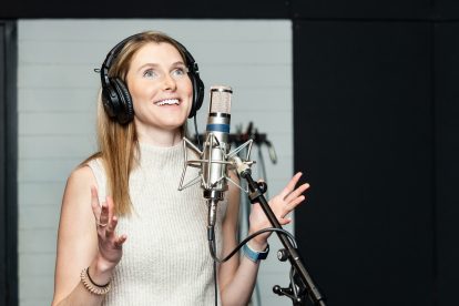 A blonde woman speaks into microphone in a studio.