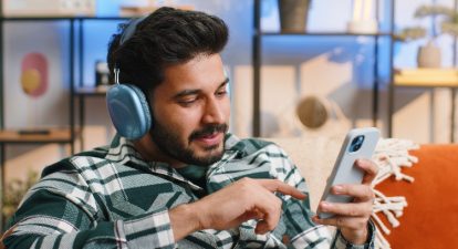Realism in advertising represented by a man wearing headphones and using a smartphone.