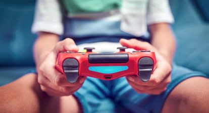 Red video game controller being held by a young man.
