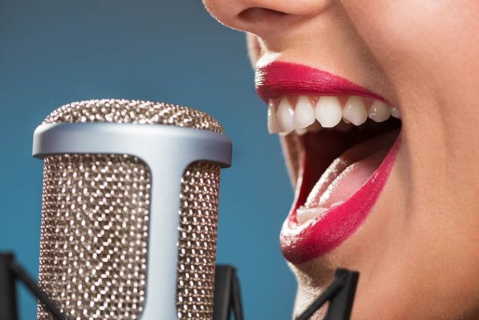 A close up of a woman singing into a condenser microphone.
