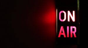 An on air sign is illuminated to the right of the image. It is lit up in red and casts a red light to the left.