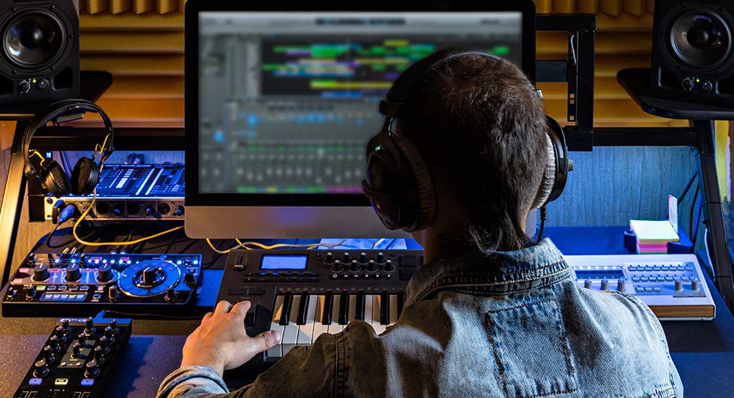 Illustration depicts a man wearing headphones sitting in front of a computer with audio editing software open.