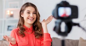 A young woman smiles as she records herself for a YouTube video.