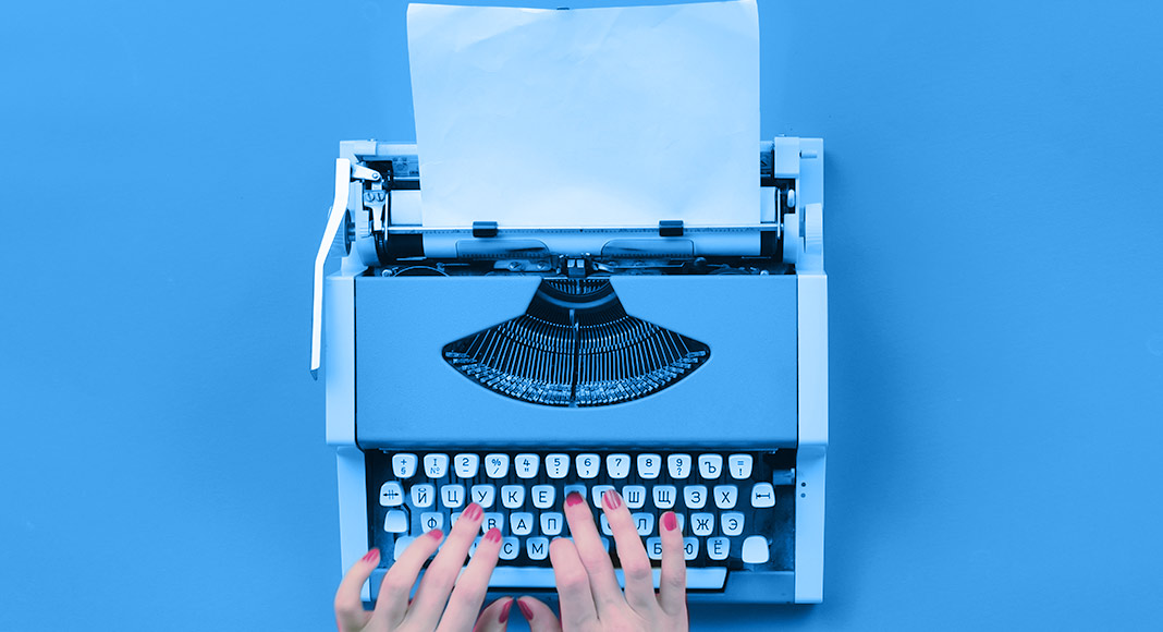 A woman types on a blue typewriter