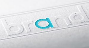 The word brand is embossed in lower case letters, diagonally across a piece of paper. The "a" is teal, while everything else is grey.
