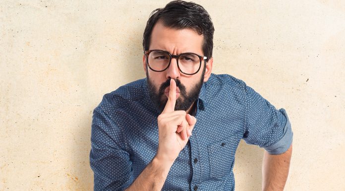 Man with finger over mouth to signal be quiet