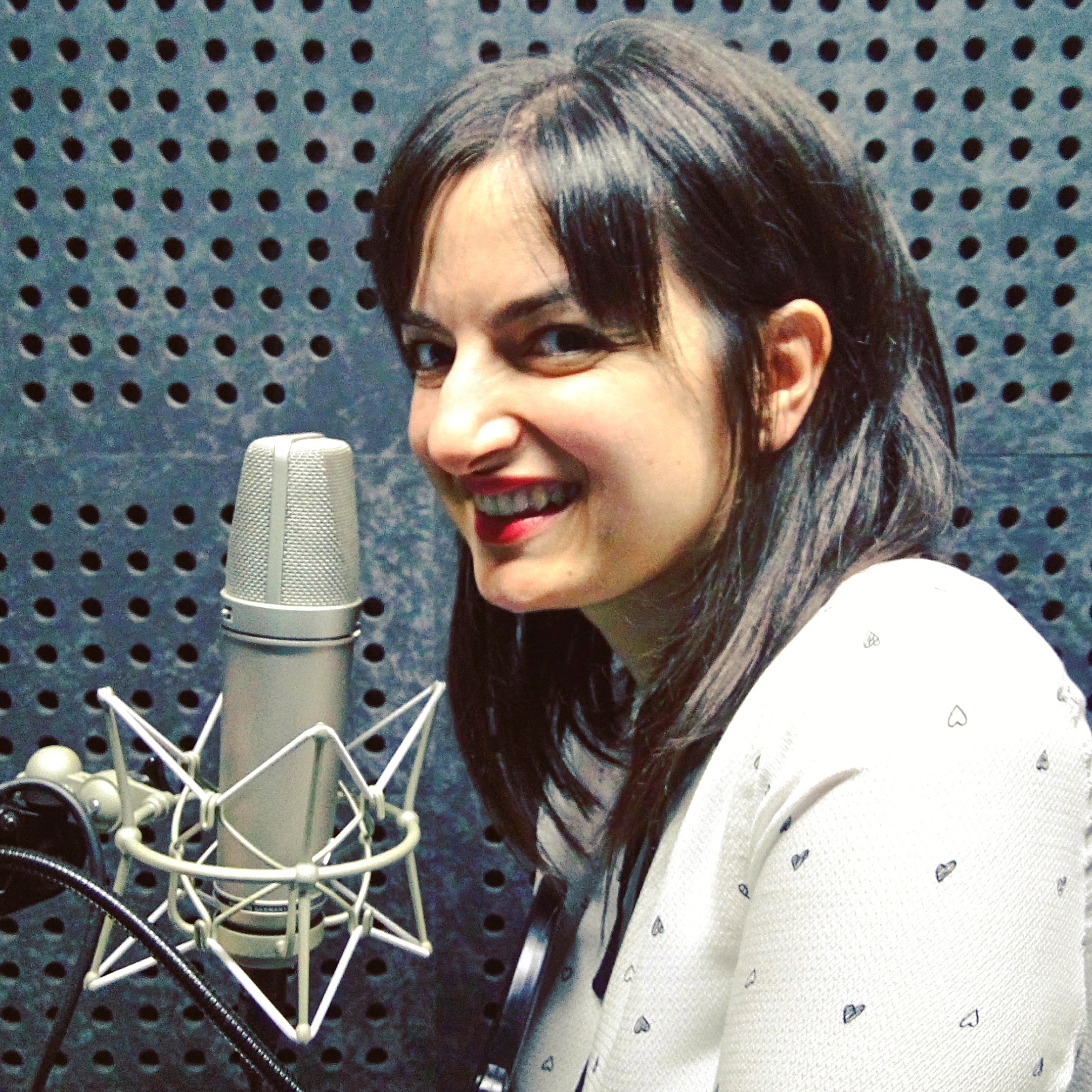 Megui Cabrera in a recording booth with a microphone.