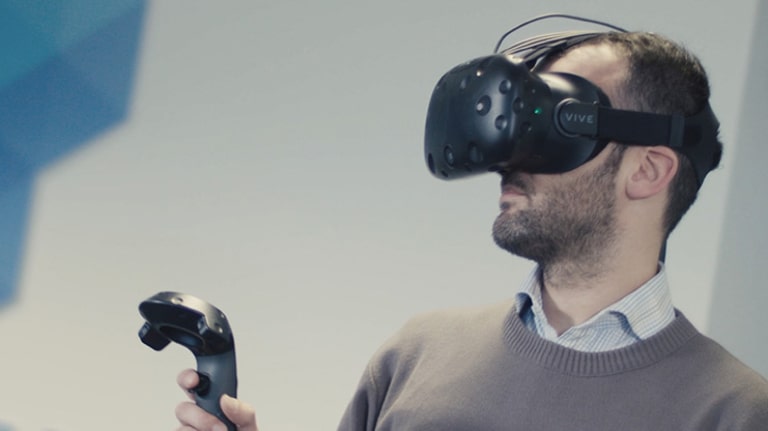 A man with a VR headset, holding up a controller.