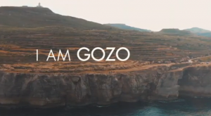 The words "I Am Gozo" displayed on a photo of the island of Gozo.