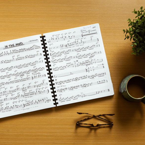 Sheet music on a table, with a cup of tea and glasses laying next to it.