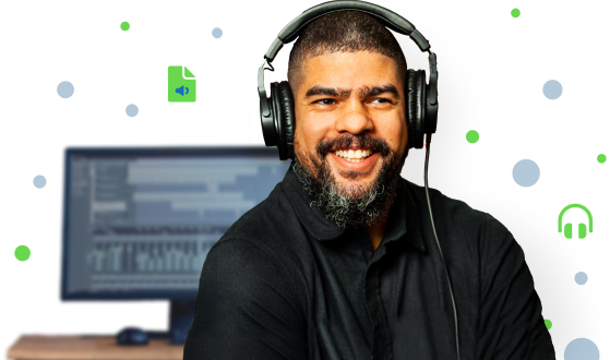 A smiling audio producer wearing headphones and standing in front of his computer.