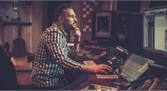 A man audio editing on his computer in a recording studio .
