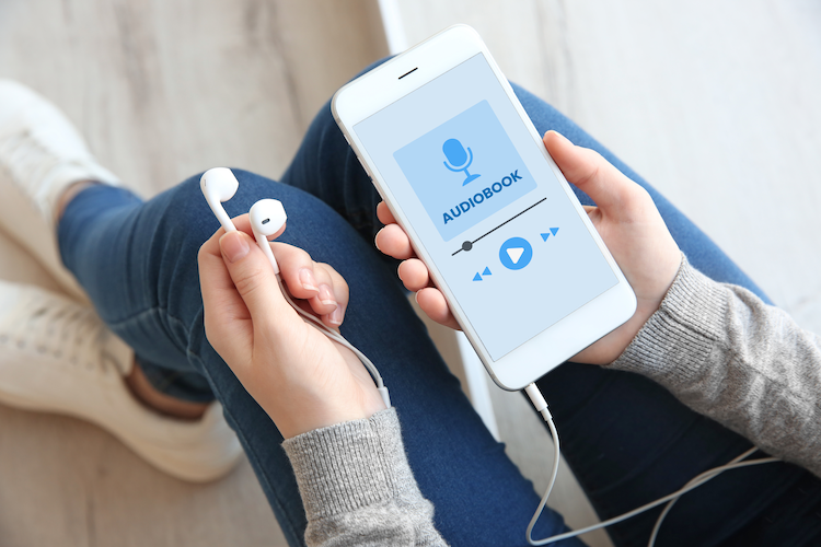 An image showing a persons hands holding a phone and listening to an audiobook