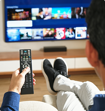 A person holds a remote while looking at a TV
